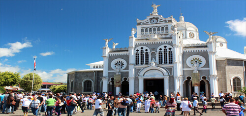 Picture a church in Costa Rica representing the vacation opportunities available for patients having dental work at Premier Holistic Dental in Costa Rica.  The picture shows many tourists and sightseers outside of the church.