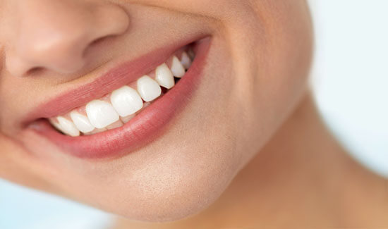 Close-up portrait picture of a smiling woman with perfect teeth, facing the camera and  illustrating her happiness with the crown lengthening procedure she had at Premier Holistic Dental in beautiful Costa Rica.