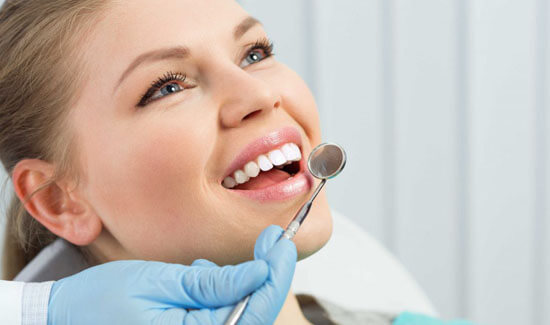 Close-up portrait picture of a smiling woman with long brown hair and perfect teeth, sitting in a dental chair and looking off to the side, showing her happiness with the dental bridges she had at Premier Holistic Dental in beautiful Costa Rica.