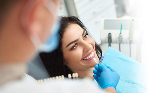 Picture of a smiling woman with long dark hair and perfect teeth, in a dental chair showing her happiness with the dental cleaning she had at Premier Holistic Dental in beautiful Costa Rica.