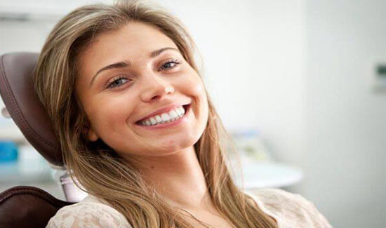 Close-up portrait picture of a smiling woman with long sandy brown hair and with perfect teeth, facing the camera and showing her happiness with the mercury-free/fluoride-free fillings she had at Premier Holistic Dental in beautiful Costa Rica.