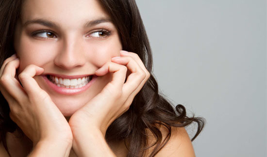 Close-up portrait picture of a smiling woman with long dark hair and with perfect teeth, looking off to the saide and showing her happiness with the periodontics procedure she had at Premier Holistic Dental in beautiful Costa Rica.