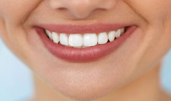 Close-up portrait picture of a smiling woman with perfect teeth, facing the camera and showing her happiness with the removal periodontal ligament procedure she had at Premier Holistic Dental in beautiful Costa Rica.