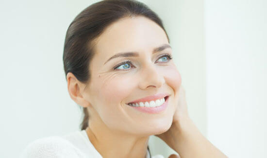 Close-up picture of a smiling woman with short dark hair and perfect teeth, looking off to the side and showing her happiness with the scaling/root-planing dental treatment she had at Premier Holistic Dental in beautiful Costa Rica.