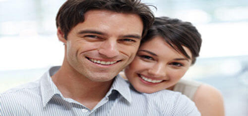 Picture of a smiling couple showing their happiness with their visit to Premier Holistic Dental in Costa Rica for dental treatment.  The woman is resting her head on the man’s shoulder and both are facing the camera with a big smile.