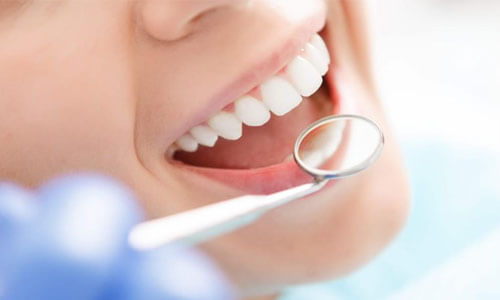 Close-up picture of a smiling young woman with perfect teeth in a dental chair happy with her Homeopathy therapy treatment she had at Premier Holistic Dental in beautiful Costa Rica.