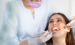 Picture of a smiling woman sitting in a dental chair having a Homeopathy treatment at Premier Holistic Dental in beautiful Costa Rica.  The picture shows a dentist performing a Homeopathy procedure on her.