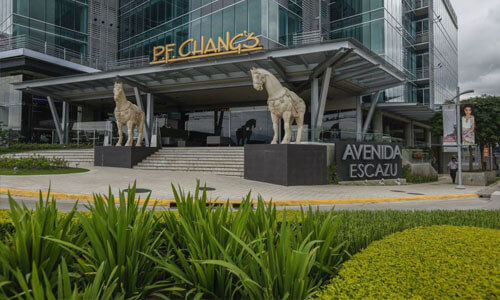 Picture of a popular restaurant at the entrance to a major shopping center in San Jose, Costa Rica.  The picture shows a tall modern office building behind the restaurant.