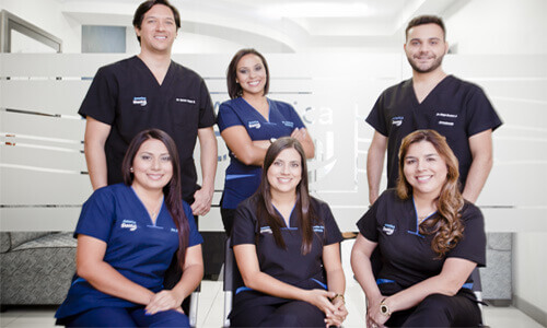 Picture of a smiling group of Premier Holistic dentists and assistants in San José, Costa Rica.  Three are standing in the back and three are sitting in front of them.