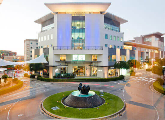 Picture of a modern office building in San José, Costa Rica,  The picture shows a  5 story building and a round-about traffic island in the bottom center of the picture.