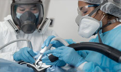 Picture of two dentists performing a safe mercury removal dental procedure at Premier Holistic Dental in beautiful Costa Rica.  The dentists have on protective suits and headgear with masks, and are using high tech equipment to remove mercury fillings.