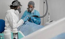 Picture of two dentists performing a Smart IAOMT Protocol Holistic dental procedure at Premier Holistic Dental in beautiful Costa Rica.  The picture shows the dentists in protective equipment and face masks.