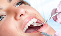 Picture of a smiling woman in a dentist chair having a teeth cleaning procedures by Premier Holistic Dental in beautiful Costa Rica..  The picture shows dental tools used by the dentist during a teeth cleaning.